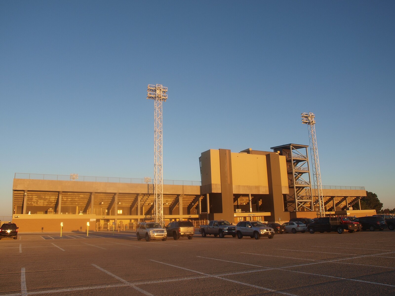 Illustrated Texas high school football players walking toward a lit stadium at sunset
