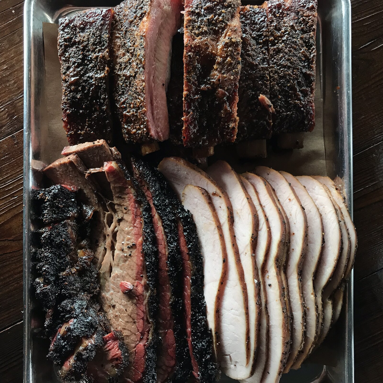 Regional Texas barbecue traditions represented by smoked brisket, sausage and live-fire cooking