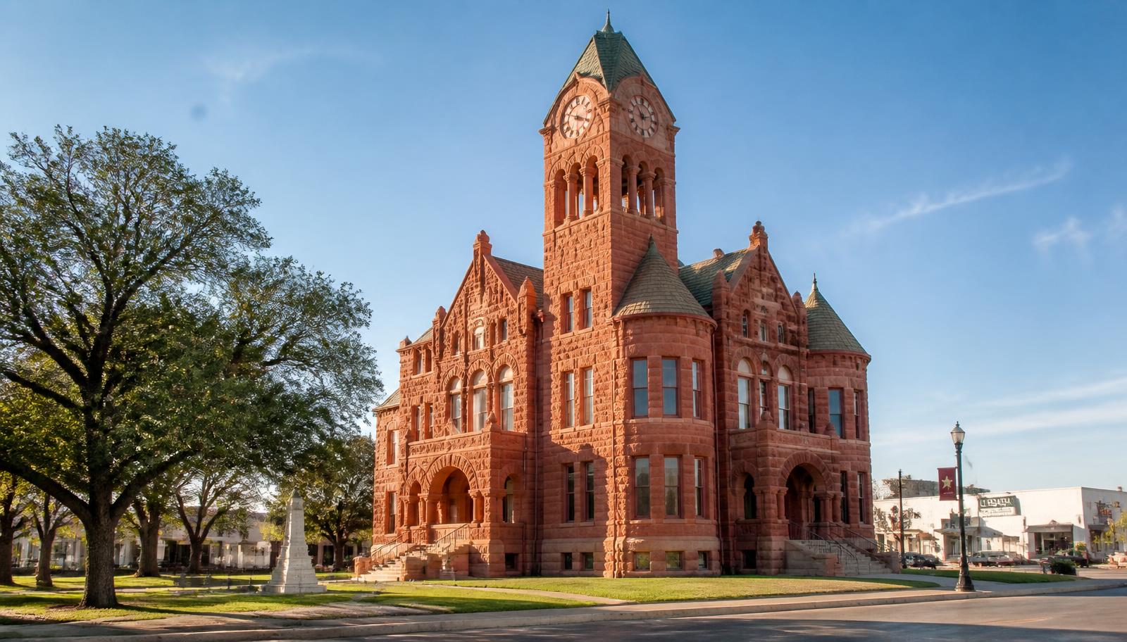 A historic red sandstone Texas county courthouse on a small-town square